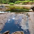Manchas escuras são encontradas no Córrego Santo Antônio após vazamento de óleo em usina de asfalto